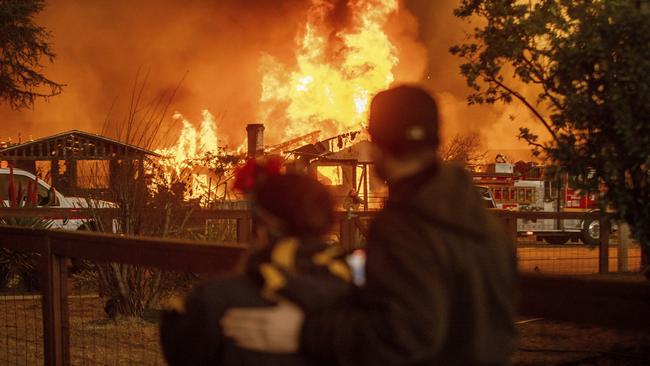 People watch as the Eaton Fire engulfs a home on Wednesday, January 8 in Altadena, California. Picture: Ethan Swope / AP