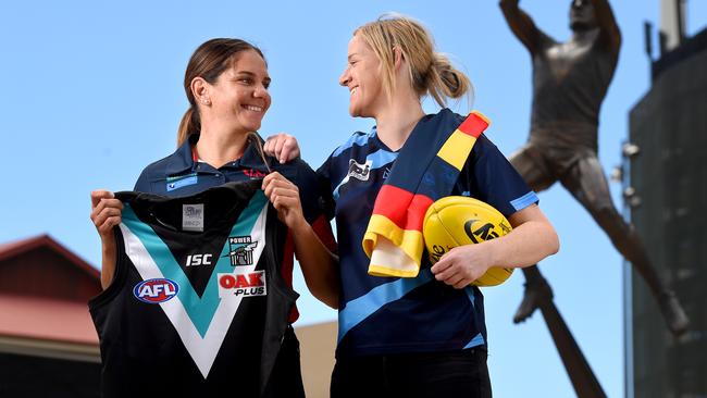 SANFL women’s players Rhiannon Busch of Norwood, with a Power jumper, and Caitlyn Swanson of Sturt, with a Crows jumper, at Adelaide Oval. Picture: Naomi Jellicoe