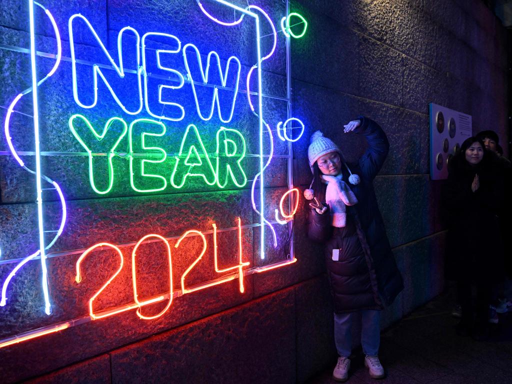 A woman poses for a photo in front of a 2024 luminous sign before a countdown event to celebrate the New Year in central Seoul on December 31, 2023. Picture: Jung Yeon-je / AFP