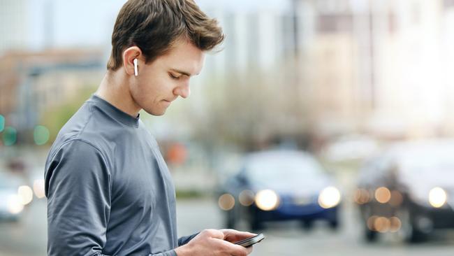 A commuter using his phones and ear buds.