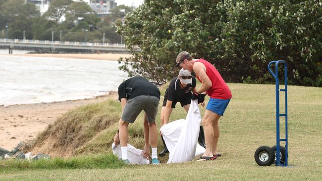 Redcliffe residents return their sandbag sand back to the beach. Picture David Clark