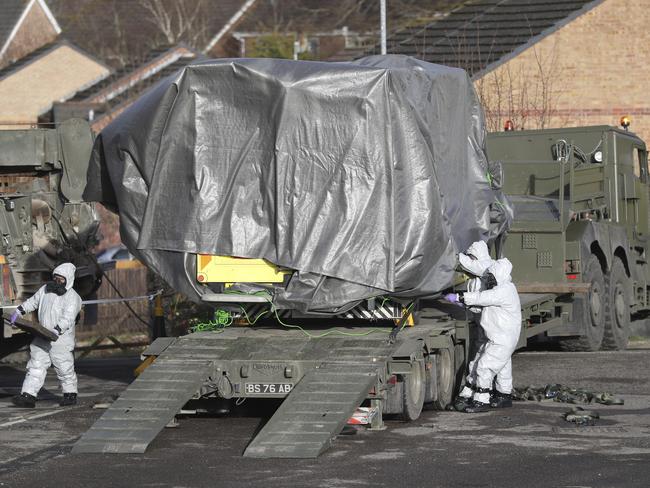 Investigators in gas masks move a wrapped ambulance from the South Western Ambulance Service station in Harnham, near Salisbury, England on Saturday. Picture: Andrew Matthews