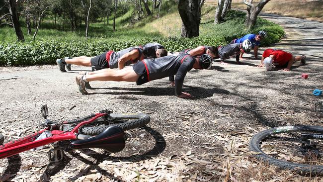 The Saints players interrupt their ride to complete some push-ups. Picture: Michael Klein