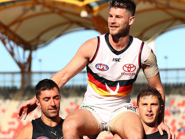 Bryce Gibbs is chaired off by Kade Simpson and Marc Murphy at Metricon Stadium.