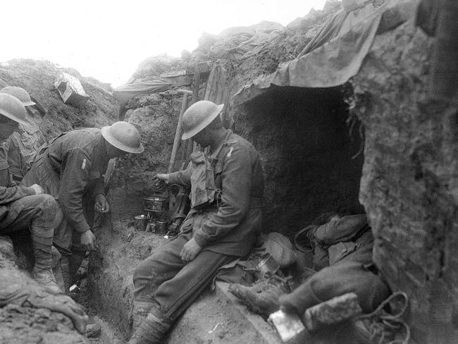 Three soldiers warm a mess tin of tea over a candle in the reserve line during the fighting near Bullecourt. Picture: : Australian War Memorial