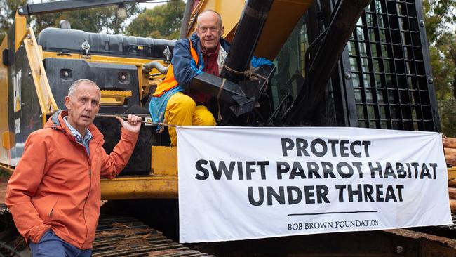 Bob Brown with forest defender attached to logging equipement. Bob Brown Foundation forest defenders have returned to contentious Eastern Tiers forests after three arrests yesterday. Logging of habitat for critically endangered Swift Parrots has been halted for a second day. Picture: BOB BROWN FOUNDATION