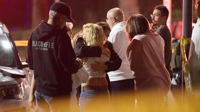 People comfort each other as they stand near the scene. Picture: AP