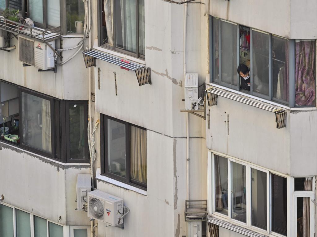 A woman looks out of an apartment during a COVID-19 lockdown in the Jing'an district in Shanghai on April 9, 2022. Picture: Hector Retamal / AFP