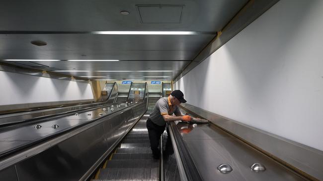 An employee at Bondi Junction Station disinfects escalator handrails in Sydney. Picture: Getty Images