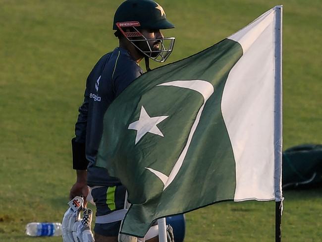 (FILES) In this file photo taken on September 16, 2021, Pakistan's captain Babar Azam walks past a national flag as he arrives to bat during a practice session at the Rawalpindi Cricket Stadium in Rawalpindi. - Virat Kohli's India begin the Twenty20 World Cup as one of the favourites and take on arch-rivals Pakistan in Dubai on October 24, 2021. (Photo by Aamir QURESHI / AFP)