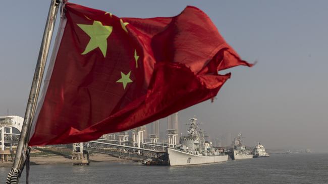 A Chinese national flag flies from a ferry near warships docked on the Yangtze River in Wuhan. Picture: Qilai Shen/Bloomberg