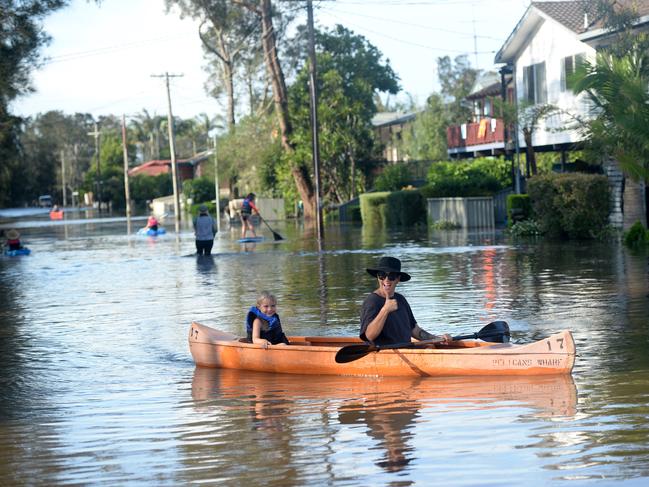 Residents of Geoffrey Road in Chittaway Bay, take to the flooded street in water craft. Photo: Jeremy Piper