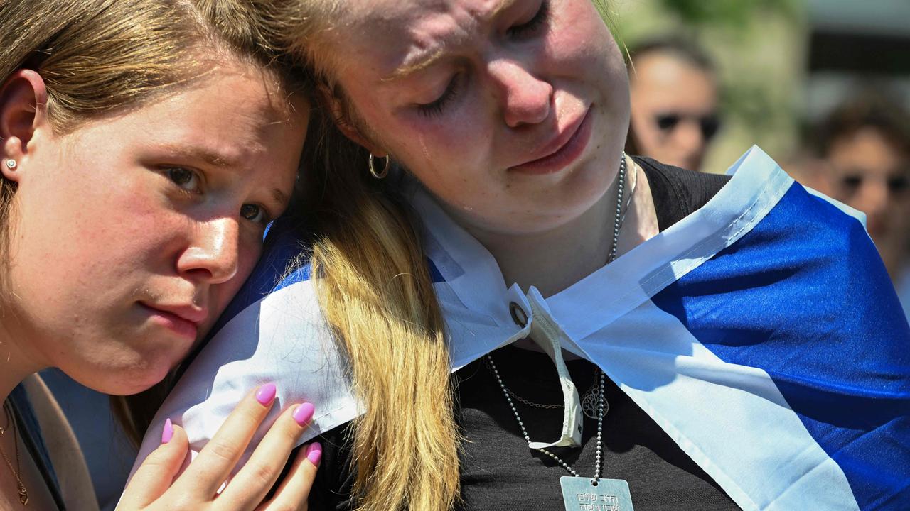 Emma (R) sheds a tear as she and her friend Aryn (L) listen to the names of the Israeli hostages currently being held by Hamas in Gaza as they gathered with others to attend a George Washington University rally against Campus Semitism during the event in a park in Downtown Washington, DC on May 02, 2024. (Photo by ROBERTO SCHMIDT / AFP)