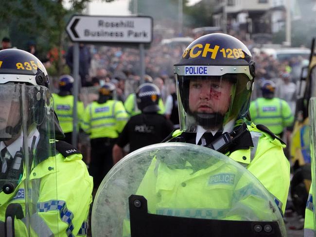 Riot police hold back protesters near a burning police vehicle after disorder broke out on July 30 in Southport, England. Picture: Getty Images)