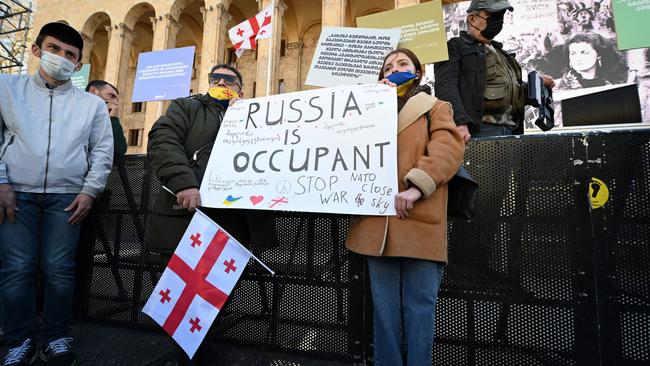 Protesters hold a placard and Georgian flags during a demonstration against Russia's invasion of Ukraine outside the parliament building in Tbilisi, on April 9. Picture: Vano Shlamov/AFP