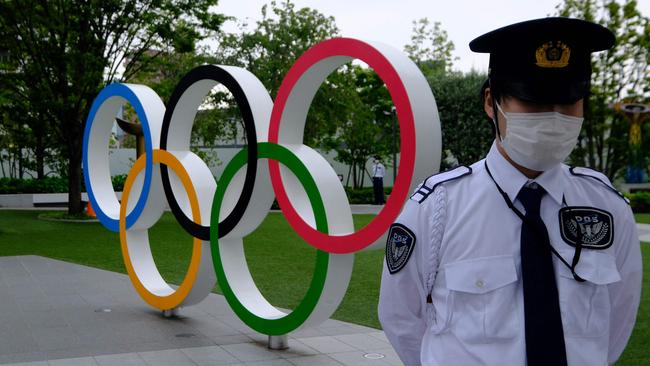 A security guard keeps watch next to the Olympic Rings outside the headquarters of the Japanese Olympic Committee in Tokyo. Picture: AFP