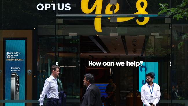 Pedestrians walk past a security guard standing outside an Optus outlet in Sydney on November 9. Picture: David Gray/AFP