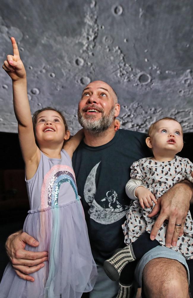 Mark Hartmann of South Brisbane with daughters Saskia, 4 and Zadie, 18 months enjoy looking at the moon inside the Cosmic Skydome at the Sir Thomas Brisbane Planetarium. Picture: Zak Simmonds