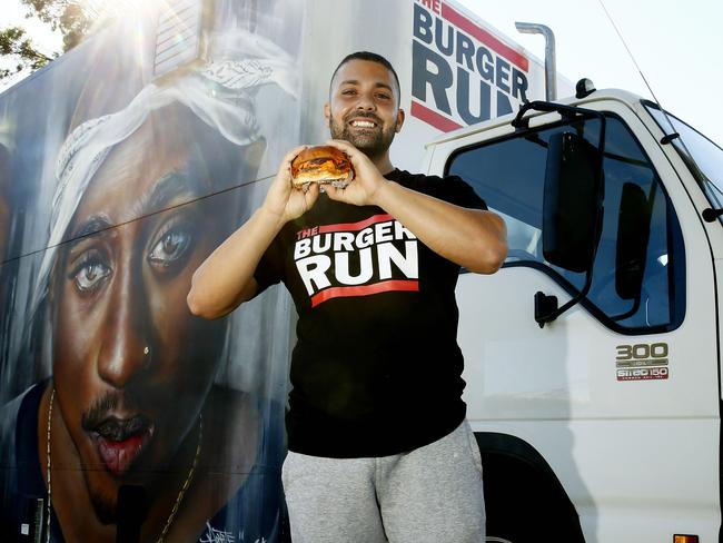 Aziz Ishak with a burger and the Mural of Rappers Biggie Smalls and Tupac Shakur on his Burger Run truck. The Burger Run mobile burger truck, with it's distinctive rap inspired artwork, is coming to Parramatta. Picture: John Appleyard