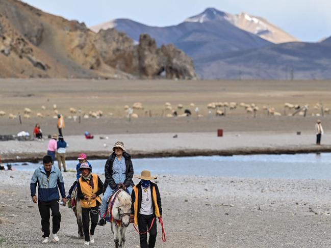 This photograph taken on June 2, 2021 during a government organised media tour shows tourists riding horses at Namtso lake in Dangxiong county, known in Tibetan as Damxung county, in China's Tibet Autonomous Region. - Thirty-five million tourists flooded into the region last year, ten times the entire population of Tibet -- prompted warnings that the influx could overwhelm traditional lifestyles and values. (Photo by Hector RETAMAL / AFP) / TO GO WITH China-Tibet-tourism-lifestyle,FOCUS by HELEN ROXBURGH