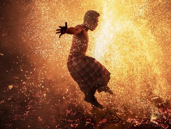 In Bali, a man partakes in the mesabatan api, a fire ritual involving leaping through coconut husk flames. Picture: Agung Parameswara/Getty Images