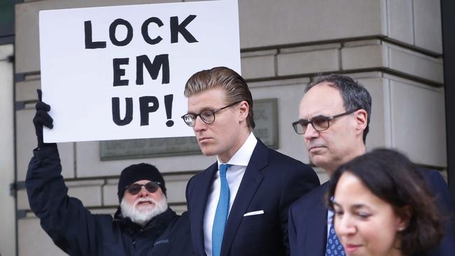 Alex van der Zwaan leaves Federal District Court in Washington as a protester holds a sign saying ‘lock em up’. Picture: AP