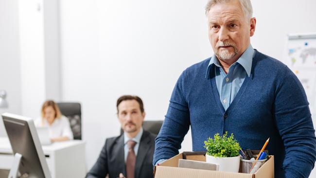 Quitting my responsibilities here. Fired involved aging employee standing and holding the box with his belongings while leaving the office