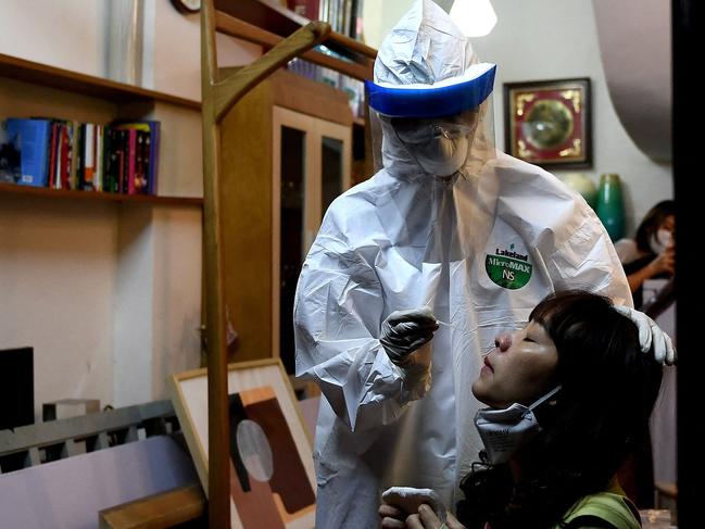 (FILES) In this file photo taken on March 30, 2020, a health worker, wearing protective clothing amid concerns of the spread of the COVID-19 coronavirus, conducts a swab test on a woman in her house in Hanoi. - Vietnam announced the discovery of a new Covid-19 variant which spreads quickly by air and is a combination of the Indian and UK strands, state media reported on May 29, 2021. (Photo by Nhac NGUYEN / AFP)