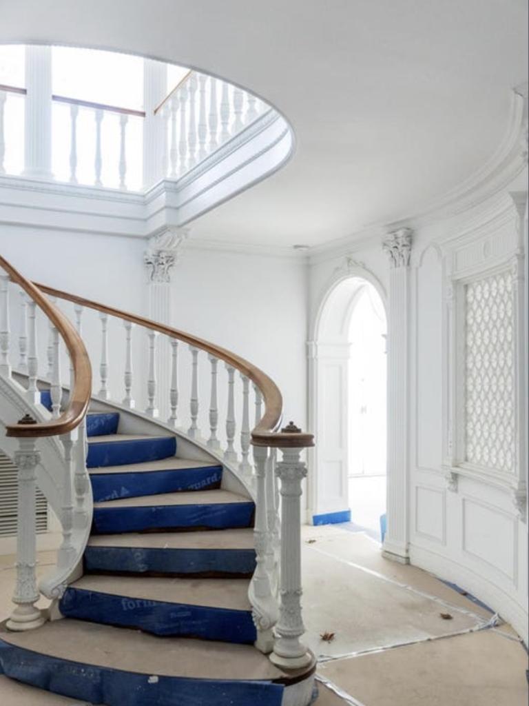 Time and neglect have taken their toll, but the curved staircase and original balustrade remain intact, offering a focal point for restoration.