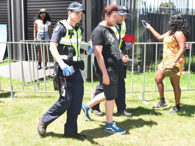 A man is being taken away for a drug search. Picture: Tony Gough