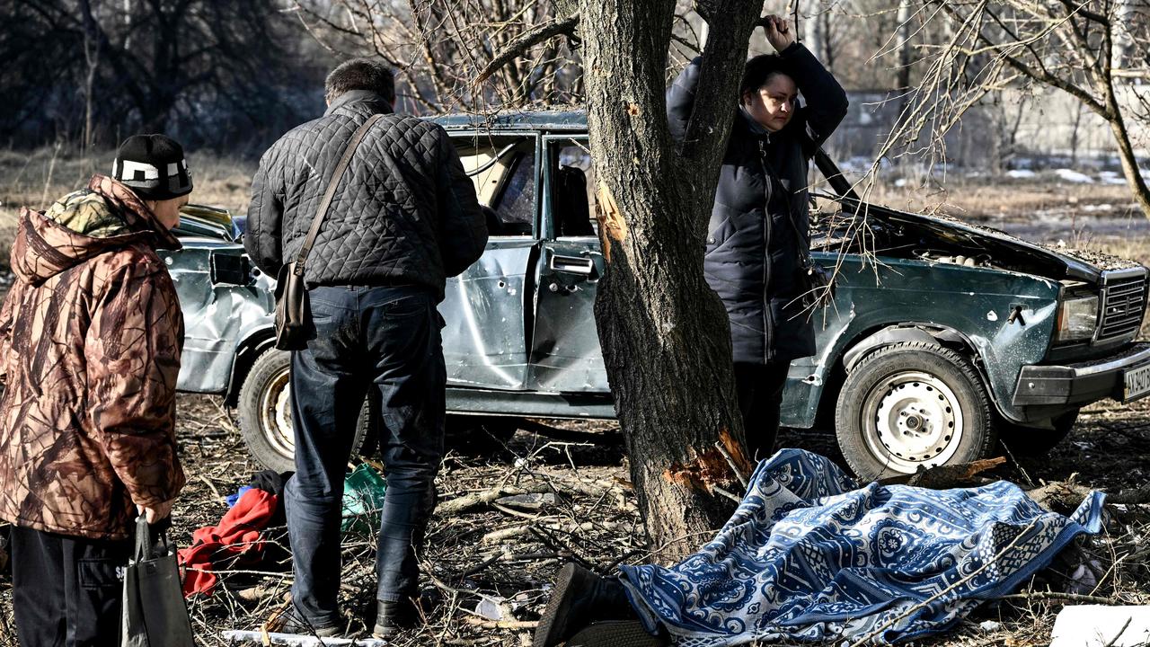 People stand by the body of a relative stretched out on the ground after bombings on the eastern Ukraine town of Chuguiv. Picture: Aris Messinis / AFP