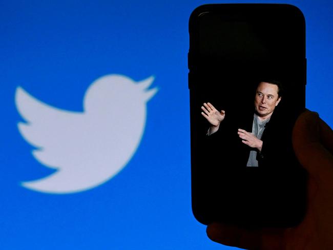 (FILES) In this file photo taken on October 4, 2022, a phone screen displays a photo of Elon Musk with the Twitter logo shown in the background, in Washington, DC. - Twitter said it will start laying off employees on November 4, 2022, as the new billionaire owner Elon Musk moves quickly after his big takeover to make the messaging platform financially sound. (Photo by OLIVIER DOULIERY / AFP)