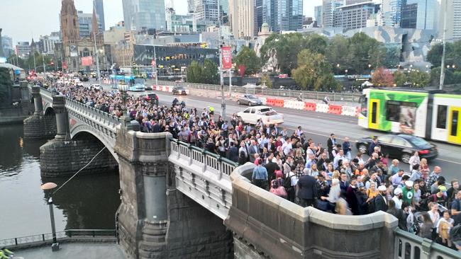 Melbourne commuters queue across Princes Bridge for a bus. Picture: Rob Baird