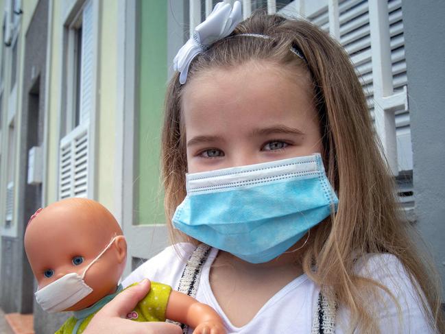 Naidelin, 5, and her doll pose wearing a face mask in the street in Santa Cruz on the Canary Island of Tenerife, on April 26, 2020 during a national lockdown to prevent the spread of the COVID-19 disease. - After six weeks stuck at home, Spain's children were being allowed out today to run, play or go for a walk as the government eased one of the world's toughest coronavirus lockdowns. Spain is one of the hardest hit countries, with a death toll running a more than 23,000 to put it behind only the United States and Italy despite stringent restrictions imposed from March 14, including keeping all children indoors. Today, with their scooters, tricycles or in prams, the children accompanied by their parents came out onto largely deserted streets. (Photo by DESIREE MARTIN / AFP)