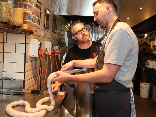 Anthony Huckstep watches chef Shannon Debrency at LP's Quality Meats make sausages. Picture: James Croucher