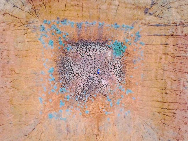 Farmer Ash Whitney stands in the middle of a dried-up dam in a drought-effected paddock on his property west of Gunnedah in NSW on June 3. Picture: David Gray/Reuters