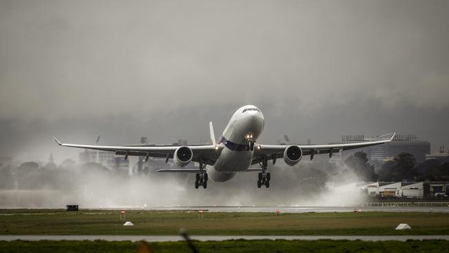 A plane takes off on a wet runway at Adelaide Airport. Picture: Mike Burton