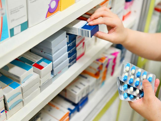 Pharmacist holding medicine box and capsule pack in pharmacy drugstore.