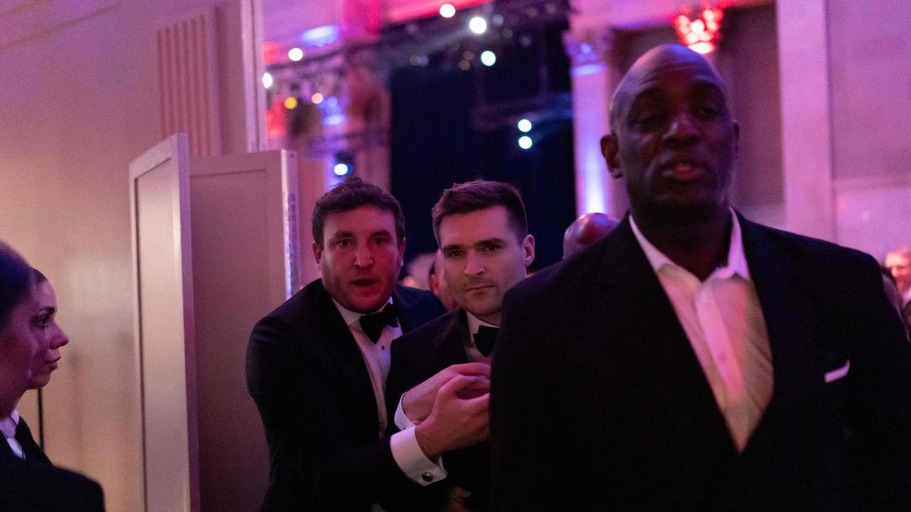 US political strategist Alex Bruesewitz (centre) is escorted backstage after collapsing on stage. Picture: Adam GRAY / AFP