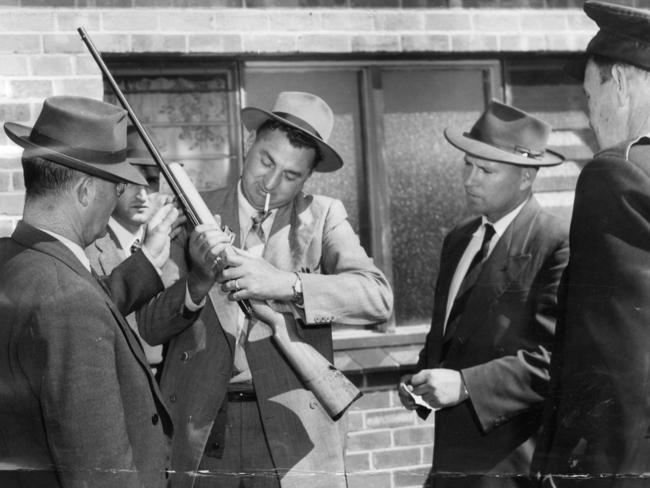 1957: Police officers examine a weapon used in the triple murder of Tom and Anna Galantomos and their daughter Phoheria at their home in Smith Street, Southwark, Adelaide.