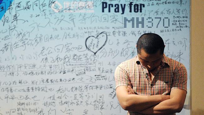 A man stands in front of a billboard in support of missing Malaysia Airlines flight MH370. AFP/Wang Zhao