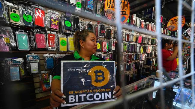 A vendor hods a sign reading ’Bitcoin accepted’ at a store in San Salvador. Bitcoin is accepted in shops but most consumers are wary. The tiny nation plans to launch ‘bitcoin bonds’ but economists are not impressed.