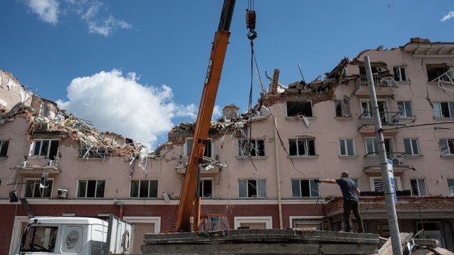 A worker is seen on top of the truck with a crane that is used to lift debris taken off a damaged Hotel Ukraine, on May 27, 2022 in Chernihiv, Ukraine. Photo by Alexey Furman/Getty Images.