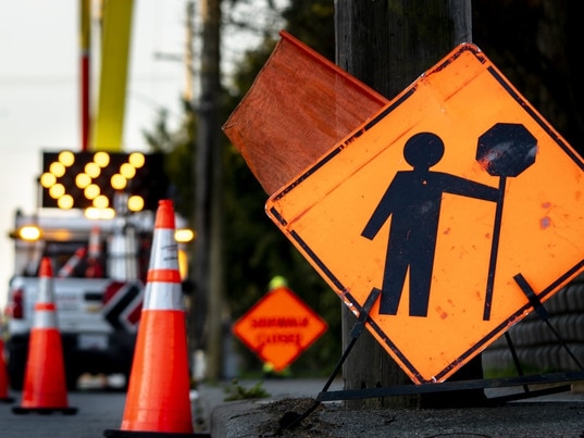 Lane closure on a busy road due to maintenance signs detour traffic temporary street work orange lighted arrow, barrels, and cones. Photo: iStock