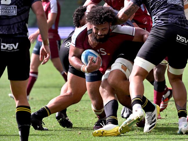 Reds player Zane Nonggorr (C) is tackled by the Hurricanes defence during the Super Rugby match between the Queensland Reds and the Wellington Hurricanes. Picture: William WEST/AFP