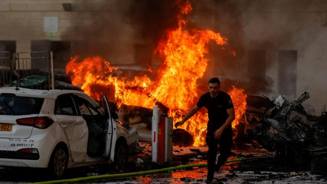 A man runs as fire burns after rockets were launched from the Gaza Strip into Ashkelon in Israel.