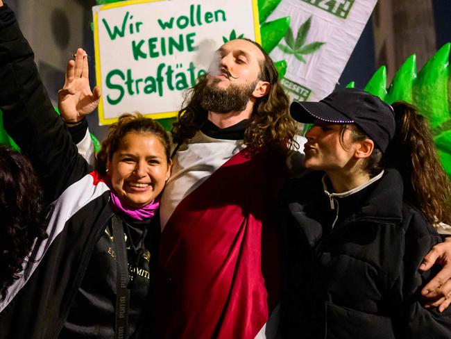 TOPSHOT - Marijuana smokers celebrate in front of a giant mock marijuana plant at a demonstration outside Berlin's Brandenburg Gate to mark the coming into force in Germany on April 1, 2024 of a law allowing adults to carry up to 25 grams of dried cannabis and grow up to three marijuana plants at home. (Photo by John MACDOUGALL / AFP)