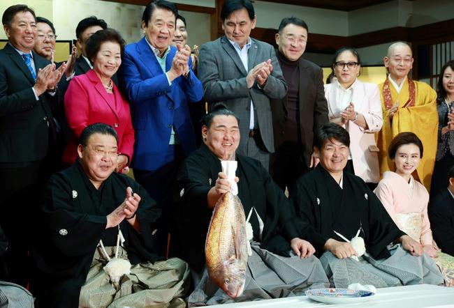 Sumo wrestler Hoshoryu holds a fish to celebrate being promoted to the sport's highest rank of yokozuna