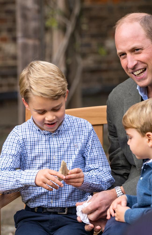 The Duke of Cambridge and Prince Louis watch as Prince George holds the tooth of a giant shark given to him by Sir David Attenborough in the gardens of Kensington Palace. Picture: Kensington Palace