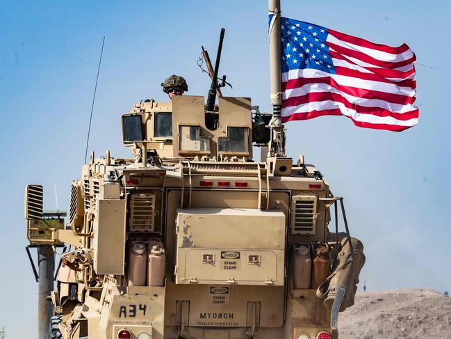 A US soldier sits atop an armoured vehicle during a demonstration by Syrian Kurds against Turkish threats on the outskirts of Ras al-Ain town in Syria's Hasakeh province. Picture: AFP